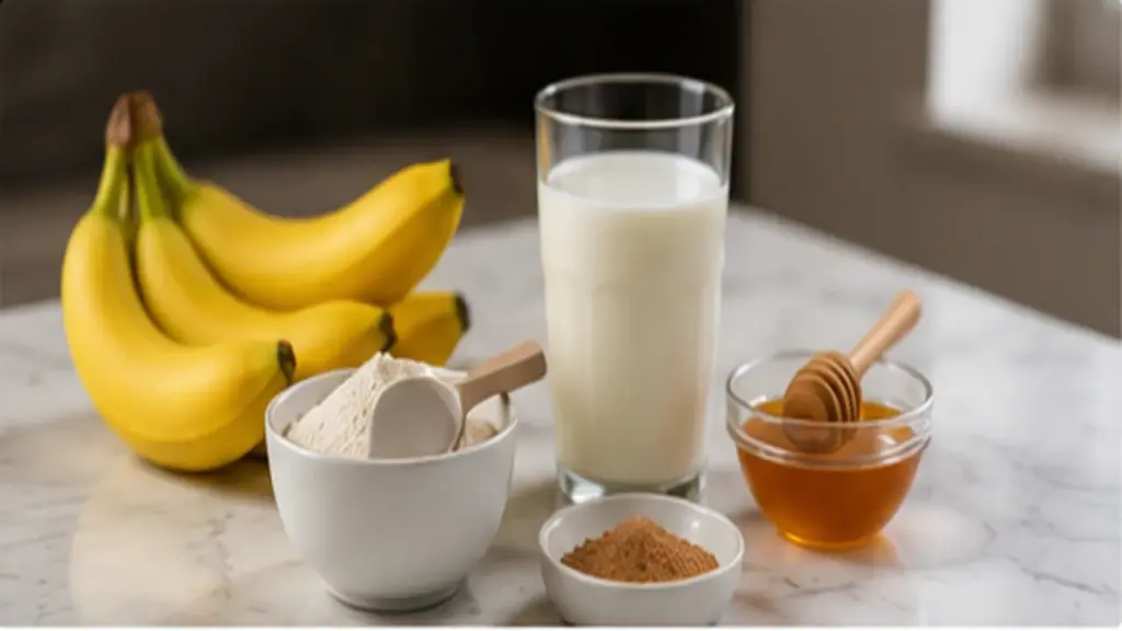 Banana, protein powder, milk, and honey arranged for a protein shake